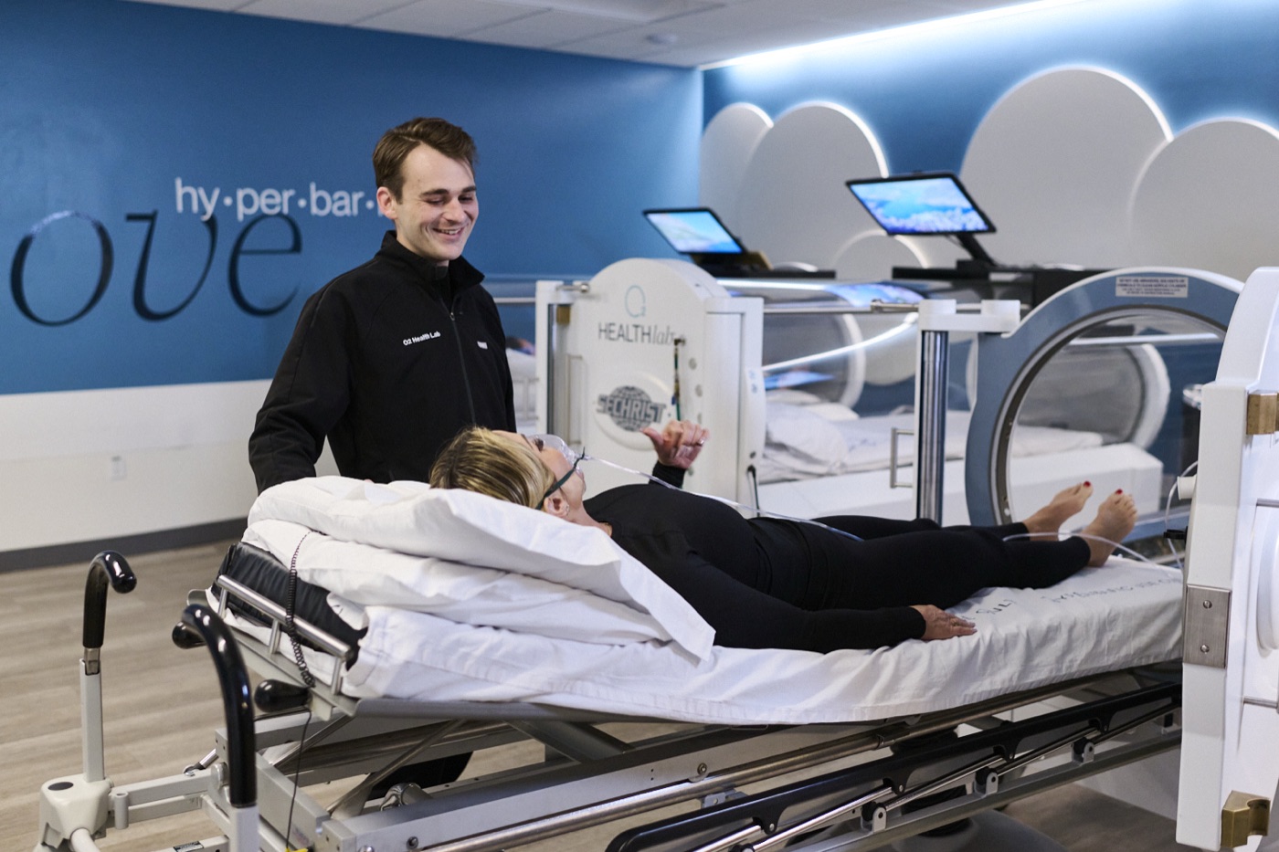 An O2 Health Lab technician smiling beside a client settling in before a session